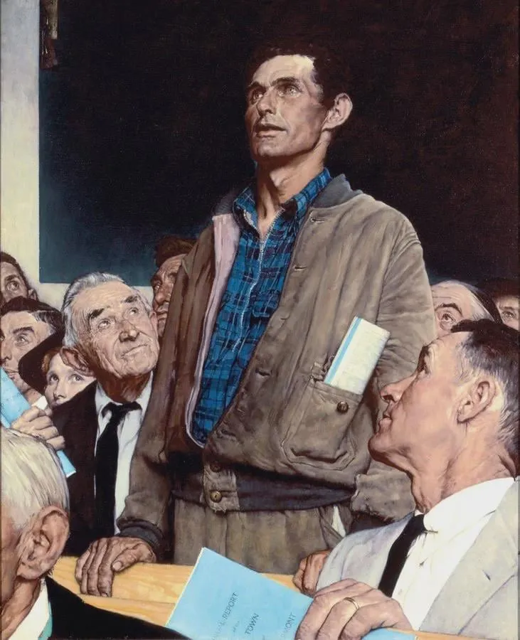 A working man standing to speak at a town meeting